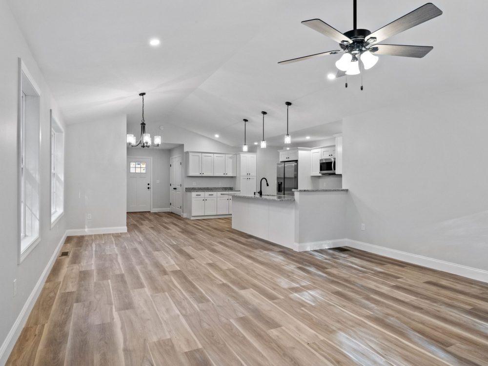 A beautiful newly renovated house corridor with hardwood floors and illuminated hanging lights