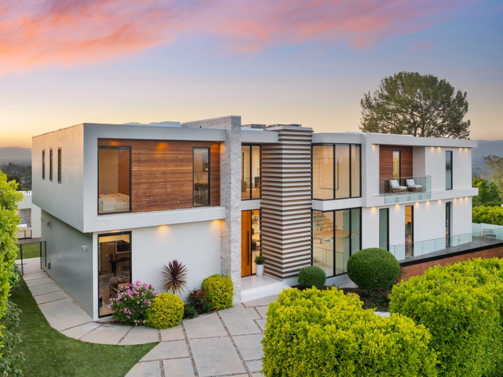 A Contemporary two-level home on hillside with shrubs and trees