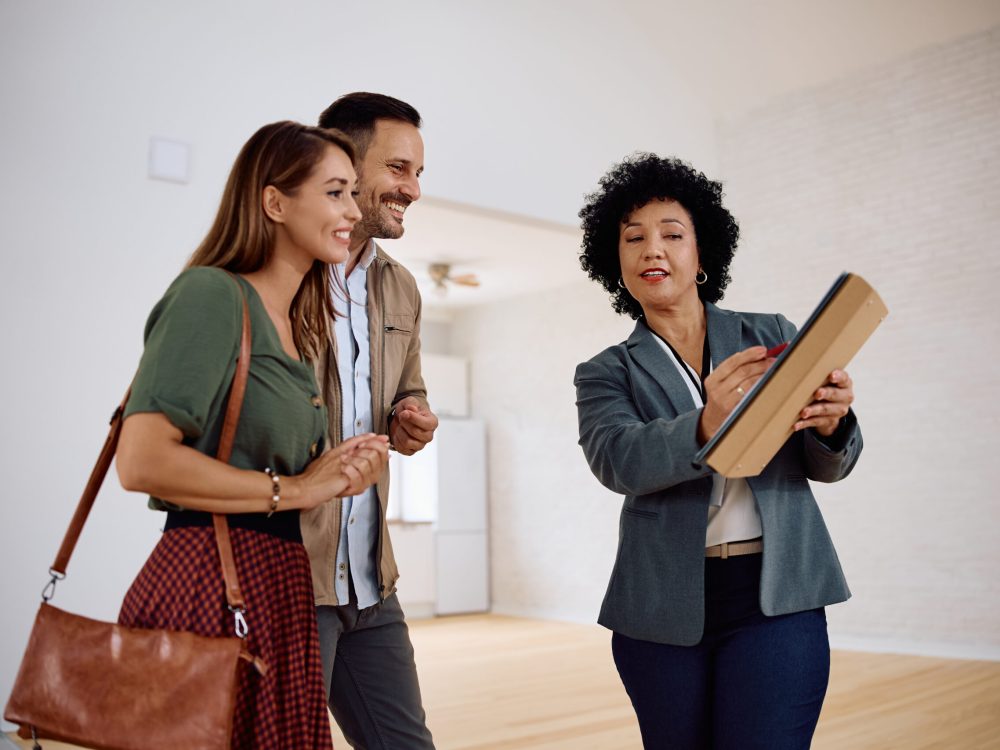 Real estate agent and young couple analyzing paperwork of a new apartment.